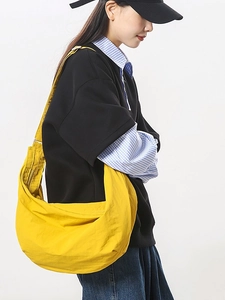 Minimalist bright yellow nylon crescent shoulder bag shown on model for daily commuting