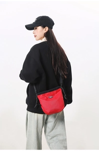 Detail of red ripstop nylon drawstring crossbody bag with woven cord and brand label