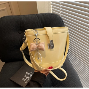 Detail of yellow glossy bucket bag with pink bow, pearl heart charm and metal clasp
