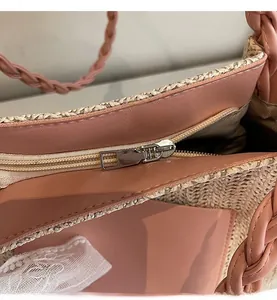 Detail of smooth metal zipper and pink leather trim on the woven summer tote bag