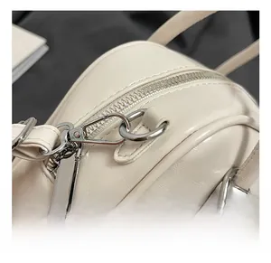 Detail of silver zipper and high-quality metal hook on minimalist cream pillow bag