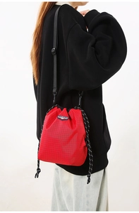 Detail of red mesh textured drawstring crossbody bag with adjustable nylon strap