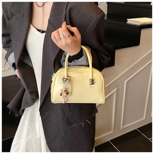 Detail of cream leather handbag featuring silver ball clasp and pearl charm accessory