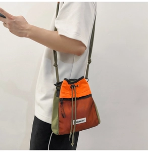 Detail der Umhängetasche aus orange-grünem Nylon mit schwarzer Netztasche am Körper