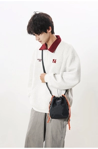 Detail of black crossbody bucket bag in ripstop nylon with orange drawstring on male model