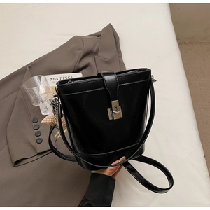 Detail of black glossy bucket bag with silver clasp, pearl charm and checkered heart