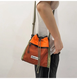Detail einer minimalistischen Tasche in Orange und Grün mit Netzstoff und Kordelzug