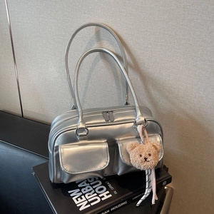 Details einer silbernen Boston Bag mit Doppeltaschen und einem Plüschbär-Anhänger