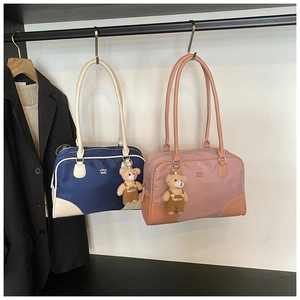 Detail of color-block nylon Boston bags featuring bear charms and embossed lettering logo