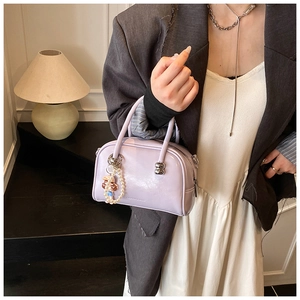 Detail of light purple bowling bag with fashion text and pearl doll charm accessory
