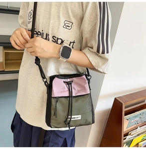 Detail der Crossbody-Tasche mit rosa Kordelzug und olivgrünem Mesh-Einsatz für Damen