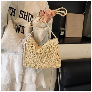 Detailed close-up of woven straw bag with white lace bow and elegant pearl charm