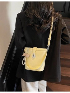 Vibrant yellow bucket bag with pearl charm and metallic lock shown on model