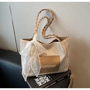 Detail of woven straw tote bag with Summer leather patch and white lace bow decoration