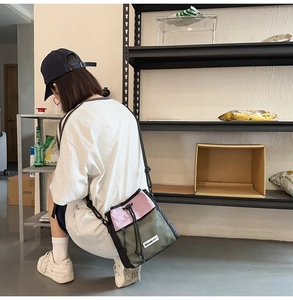 Detail der pinkfarbenen und olivgrünen Nylon-Umhängetasche mit verstellbarem Gurt am Model