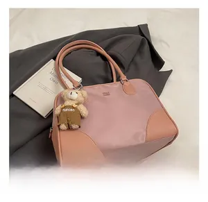 Detail of pink nylon shoulder bag with leather trim and cute bear keychain accessory