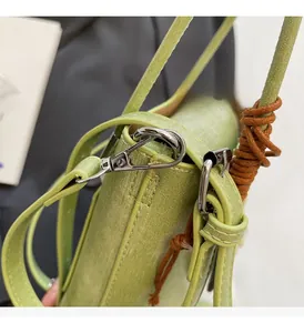 Detailed close-up of silver metal hooks and textured leather on a green crossbody bag