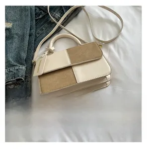 Detail of beige and khaki patchwork handbag with leather texture and hanging logo tag