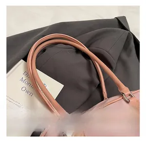 Detail of pink nylon handbag handle with silver D-rings and stitched leather texture