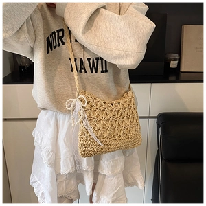 Close-up of woven straw bag detail featuring elegant pearl bow and white lace ribbons