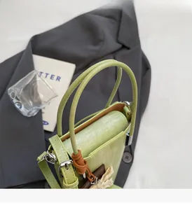 Detail of light green bucket bag with floral weave charm on a gray blazer background