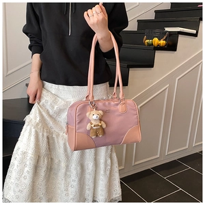 Détail du sac cabas en nylon rose avec charm ours et coins renforcés dans un escalier