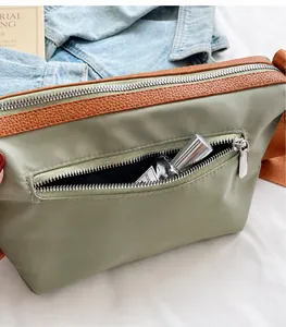 Detail of dark green nylon bucket bag featuring leather trim and external zipper pocket