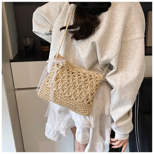 Detail of woven straw crossbody bag with white lace bow and delicate pearl accents
