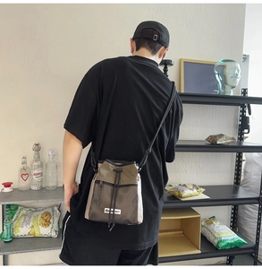 Detail der Kordelzug-Beuteltasche mit Netztasche und Markenetikett am Model getragen