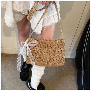 Detail of woven straw bag with star hollow pattern, lace bow, and pearl accents