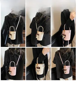 Detail view of mini bucket bag showing adjustable shoulder straps and lace bow charms