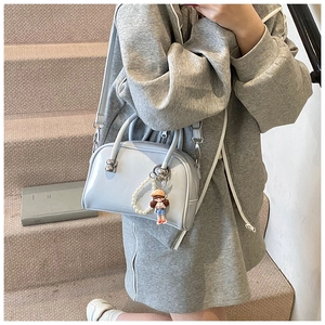 Model wearing a light blue glossy Boston bag with pearl charm and cute doll pendant