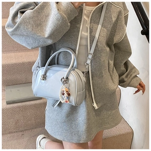 Close-up of a light blue mini Boston bag with pearl strap and cute charm on a model