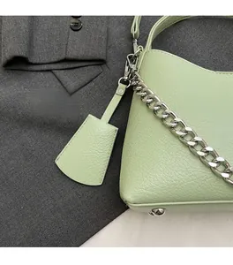 Detail of light green litchi texture leather bucket bag with silver chain and pendant
