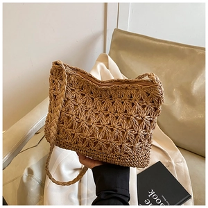 Detail of hand-woven hollow floral pattern on a straw shoulder bag with zipper closure