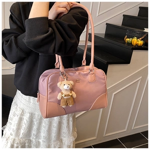 Détail du sac à bandoulière rose poudré avec breloque ours en peluche et logo en métal
