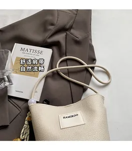 Détail du sac seau ivoire avec bandoulière en corde tressée et décoration de gland