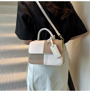 Detail of color-block crossbody bag featuring contrast stitching and fashion bag charm