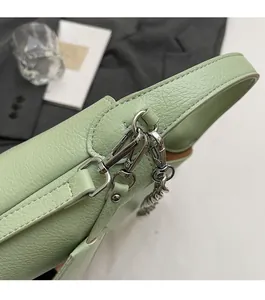 Close-up of polished silver metal chain link on mint green lychee textured leather bag