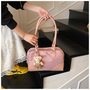 Détail du sac bowling rose avec logo et breloque ours en peluche sur les marches