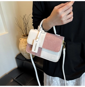 Detail of a chic pink and beige color-block handbag with a metal buckle and fashion tag