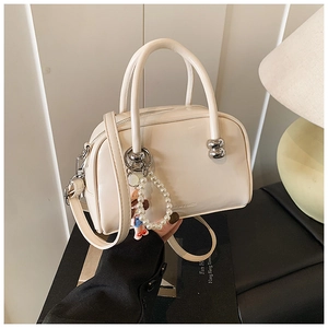 Detail of cream white Boston handbag featuring silver ball accents and a pearl pendant
