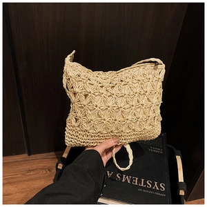 Close-up of hand-woven straw bag showing intricate hollow floral patterns and zipper