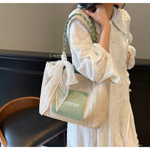 Detail of straw tote bag with mint green handle and delicate white lace bow charm