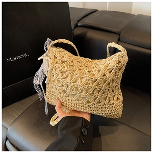 Detail of woven straw tote bag with lace bow and pearl charm for beach vacation