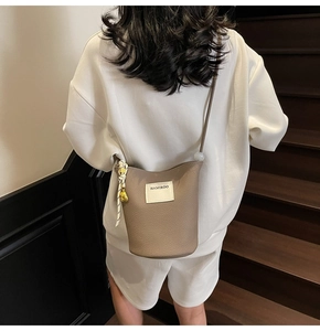 Détail du sac seau à texture litchi avec corde tressée et breloque éléphant doré