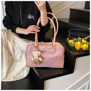 Detail of pink nylon shoulder bag featuring leather stitching and a cute bear charm