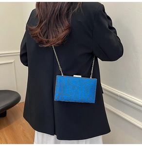 Pochette rigida leopardata blu con catena dorata indossata su un blazer nero chic