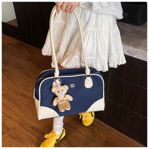 Detail view of large navy blue nylon tote bag with cream trim and cute bear charm accessory