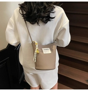 Détail d'un sac seau en cuir grainé beige avec cordon tressé et pendentif doré chic